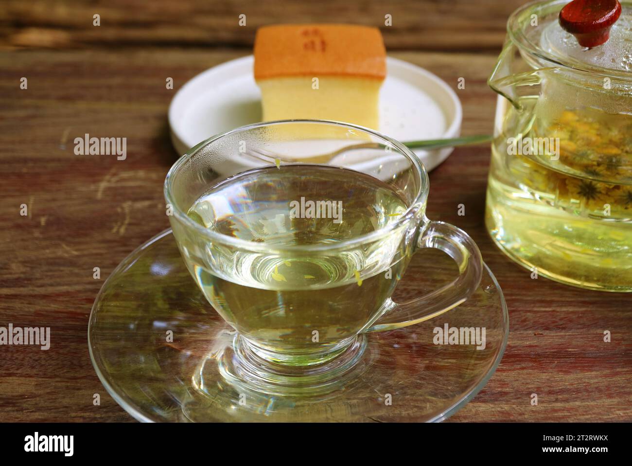 Tasse heißer Chrysanthemen-Tee mit verschwommenem taiwanesischen Castella-Kuchen im Hintergrund Stockfoto