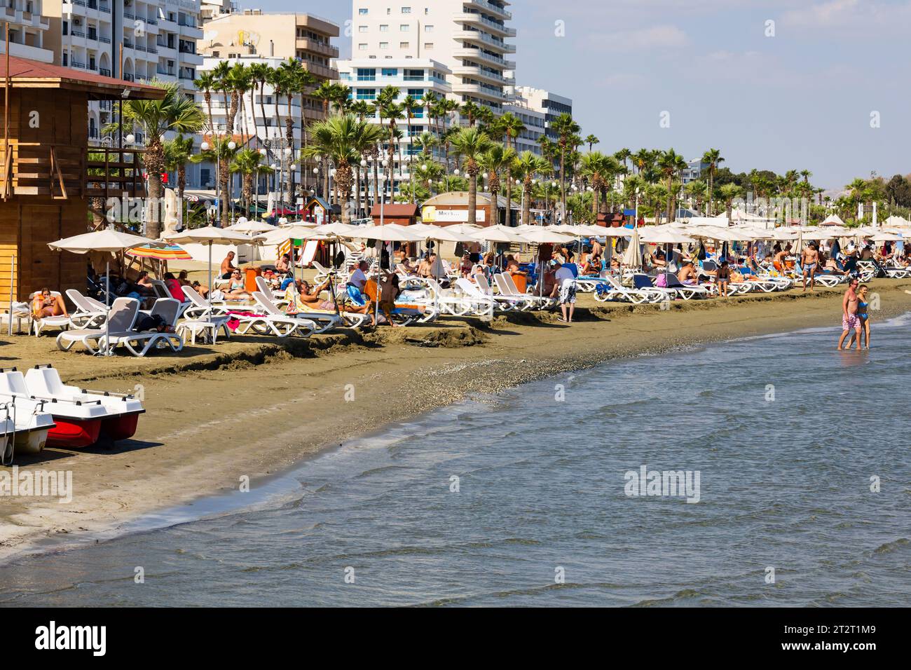 Touristen Sonnenbaden und Schwimmen am Strand von Finikoudes, Larnaca, Zypern Stockfoto
