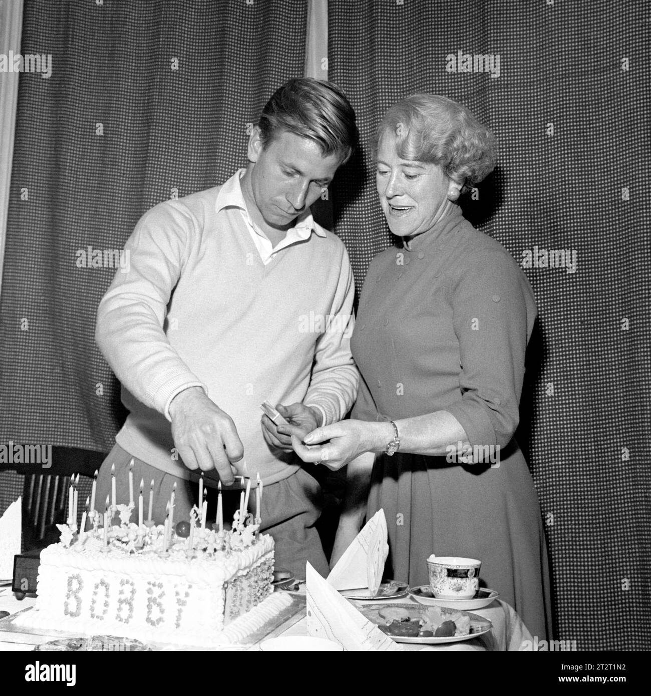 Aktenfoto vom 13.10.1958 von Manchester United und England Fußballspieler Bobby Charlton, unterstützt von seiner Mutter Betty Charlton, zündet die Kerzen an seinem 21. Geburtstag in seinem Haus in Ashington an. Sir Bobby Charlton ist im Alter von 86 Jahren gestorben, teilte seine Familie mit. Ausgabedatum: Samstag, 21. Oktober 2023. Stockfoto