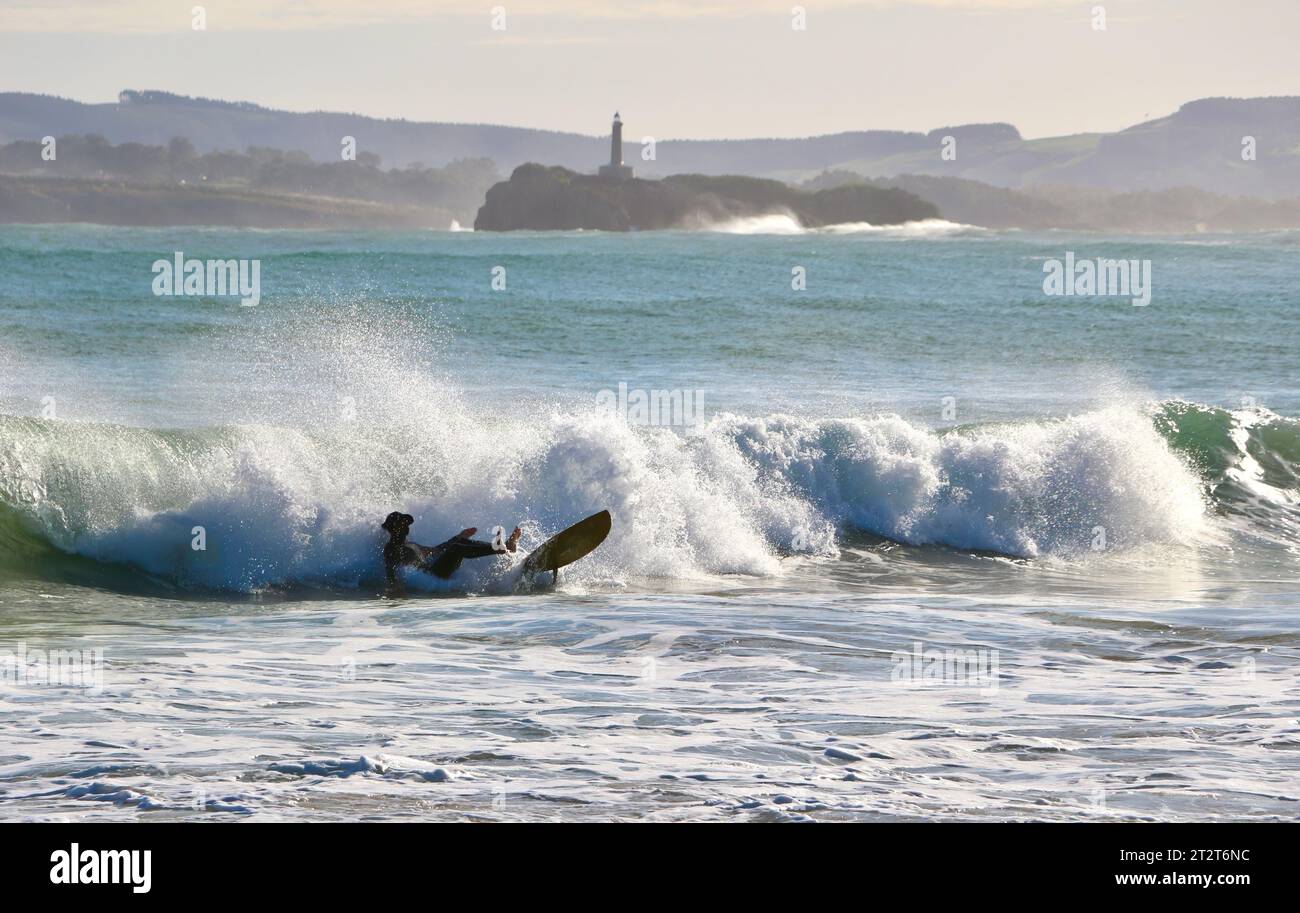 Ein Surfer mit Mouro Island am Eingang zur Bucht mit starken Wellen an einem sonnigen Herbstmorgen Sardinero Santander Cantabria Spanien Stockfoto