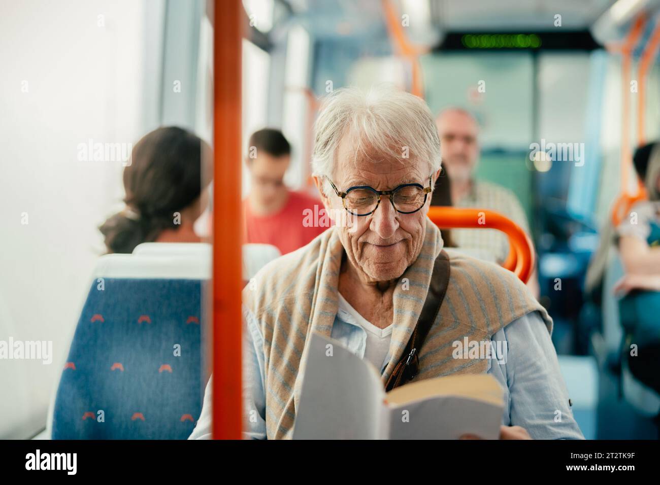 Senior Mann liest Buch, während er mit dem Bus reist Stockfoto