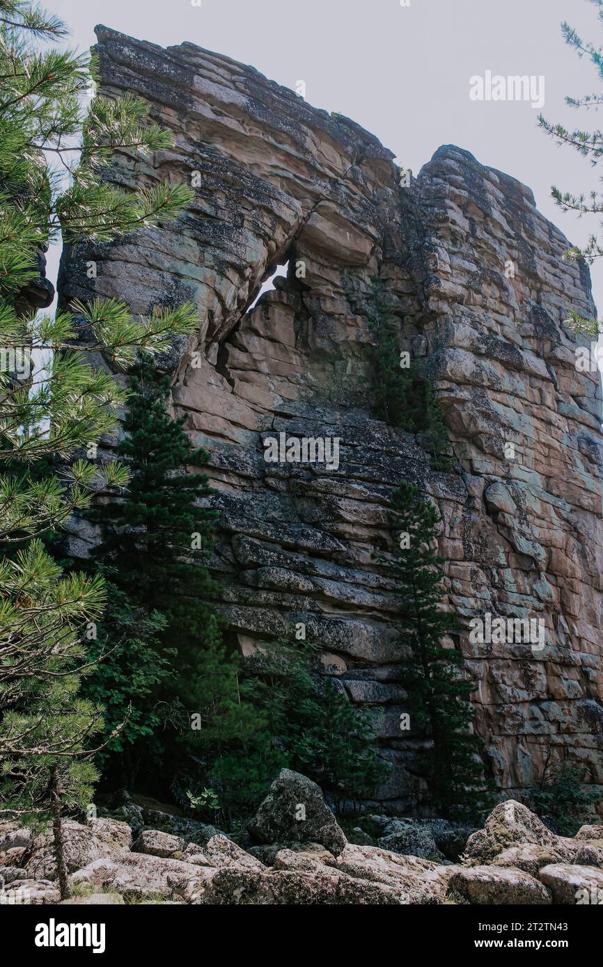 Erstaunlich geformtes hohes Syenit-Gestein mit einer magmatischen Bergformation durch das Loch. Magmaschichten. Touristenattraktion und Klettertrainingsbereich in freier Wildbahn Stockfoto