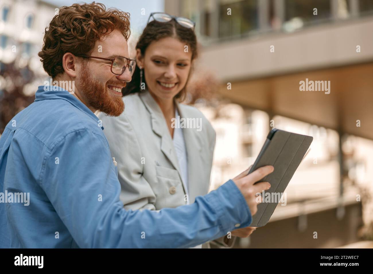 Geschäftsmann zeigt Kollegen während des Arbeitstages außerhalb des Büros etwas auf einem digitalen Tablet Stockfoto