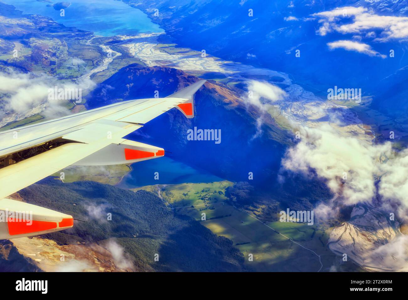 Flugzeugflügel mit Motoren, die über die Berge der Südinsel Neuseelands fliegen und über Wolken hinwegfliegen. Stockfoto