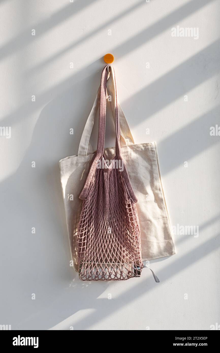 Wiederverwendbare Einkaufstaschen aus Textil und Mesh mit Wasserflasche am Haken. Stockfoto