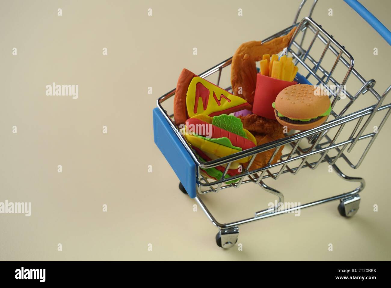 Nahaufnahme eines Einkaufswagens voller Junk Food wie Burger, Pommes und Pizza. Kopierbereich für Text. Schlechte Essgewohnheiten. Stockfoto