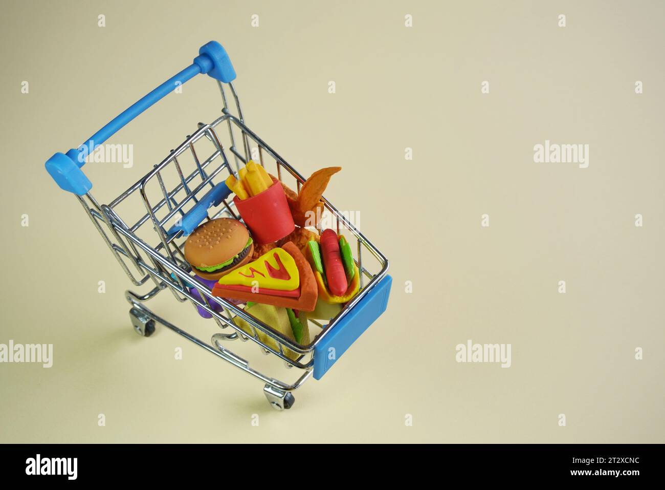 Nahaufnahme eines Einkaufswagens voller Junk Food wie Burger, Pommes und Pizza. Kopierbereich für Text. Schlechte Essgewohnheiten. Stockfoto