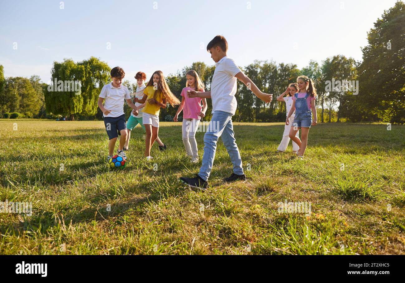Freunde Kinder Jungen und Mädchen spielen in den Sommerferien gemeinsam mit einem Ball im Freien. Stockfoto
