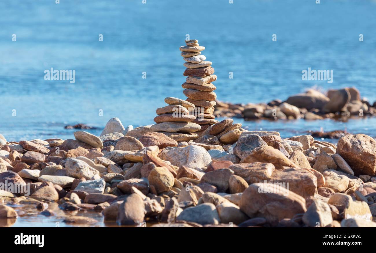 Eine Pyramide aus Kieselsteinen am Meer, vor dem Hintergrund des Meeres Stockfoto