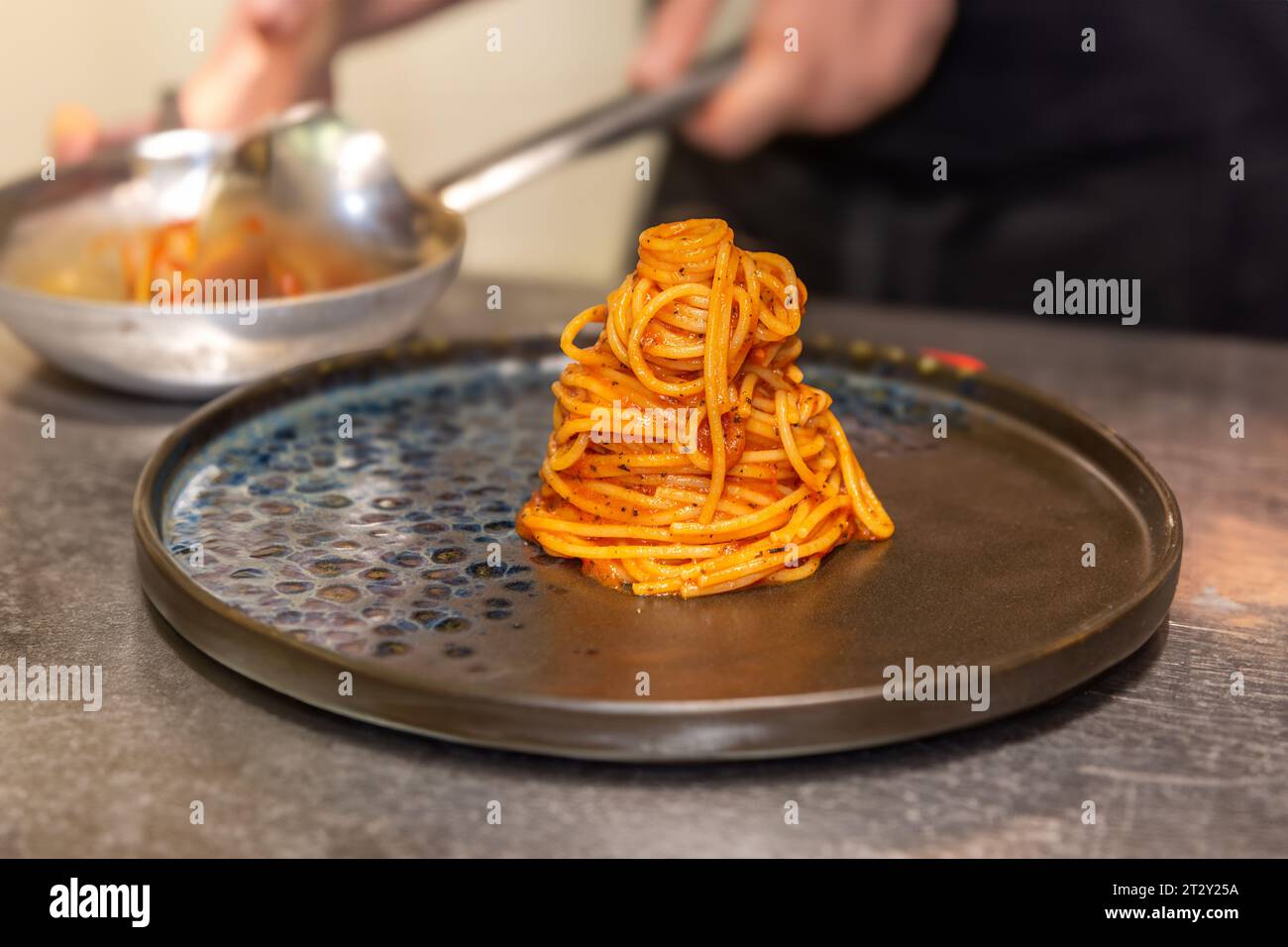Spaghetti mit Tomatensauce auf schwarzem Teller vor verschwommenem Hintergrund Stockfoto