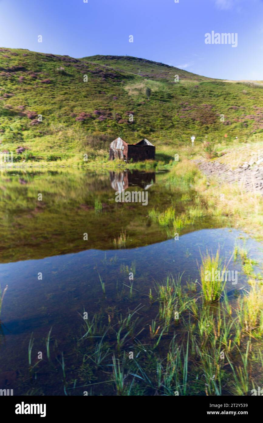 Eine Ruine einer Hütte am Rande eines Sees in Schottland an einem sonnigen Sommermorgen während eines Sommermorgens Stockfoto