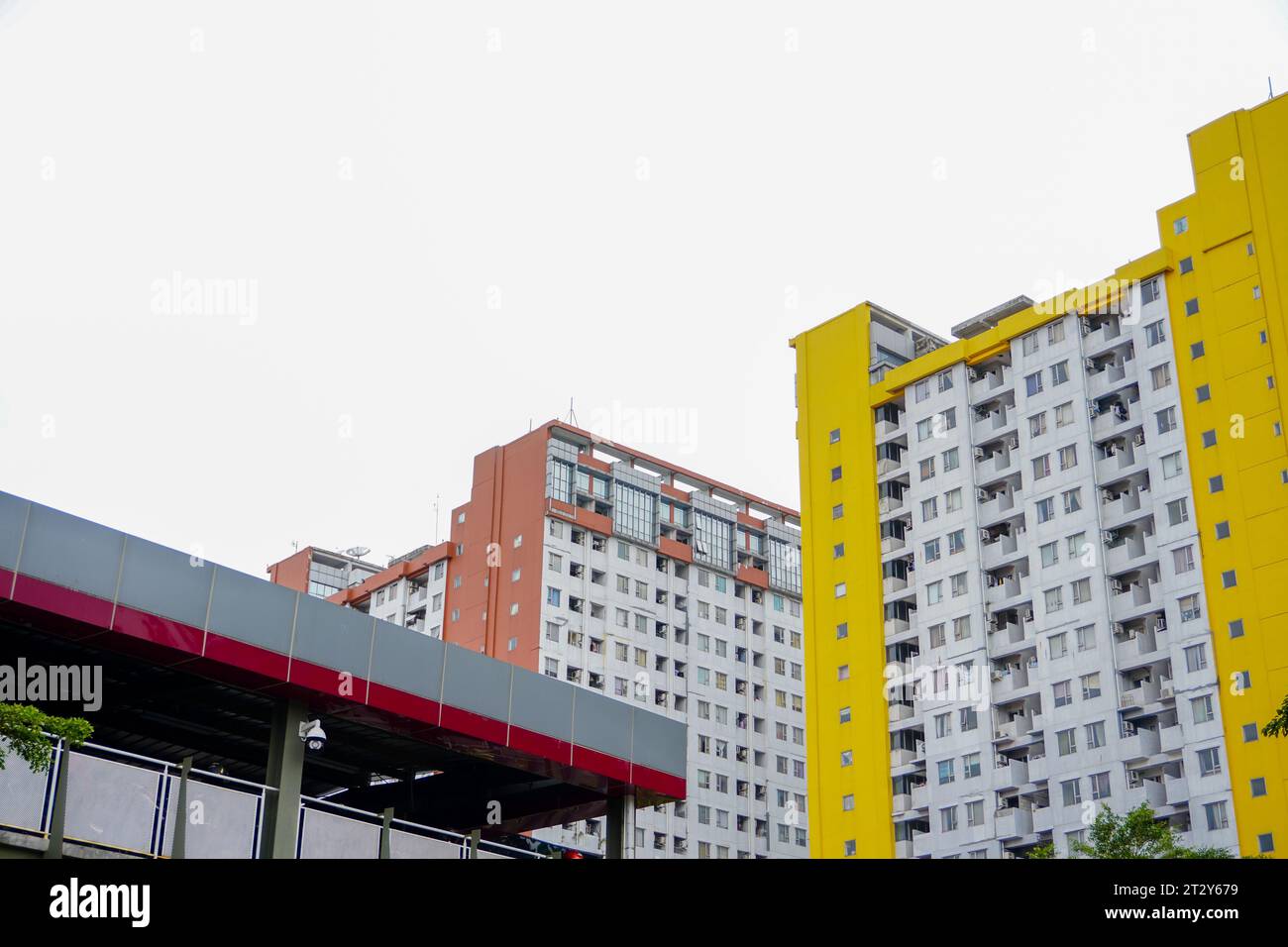 Es präsentiert ein hohes Apartmentgebäude mit einer komplexen Anordnung von Gelb- und Brauntönen, perfekt ergänzt durch einen gut ausgestatteten Parkplatz Stockfoto