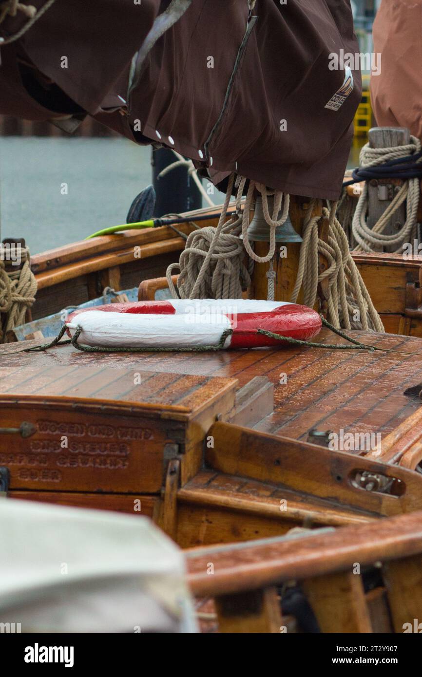 Seitenansicht eines Rettungsgurts auf Holzdeck eines alten Segelschiffs. Seile hängen um. Stockfoto