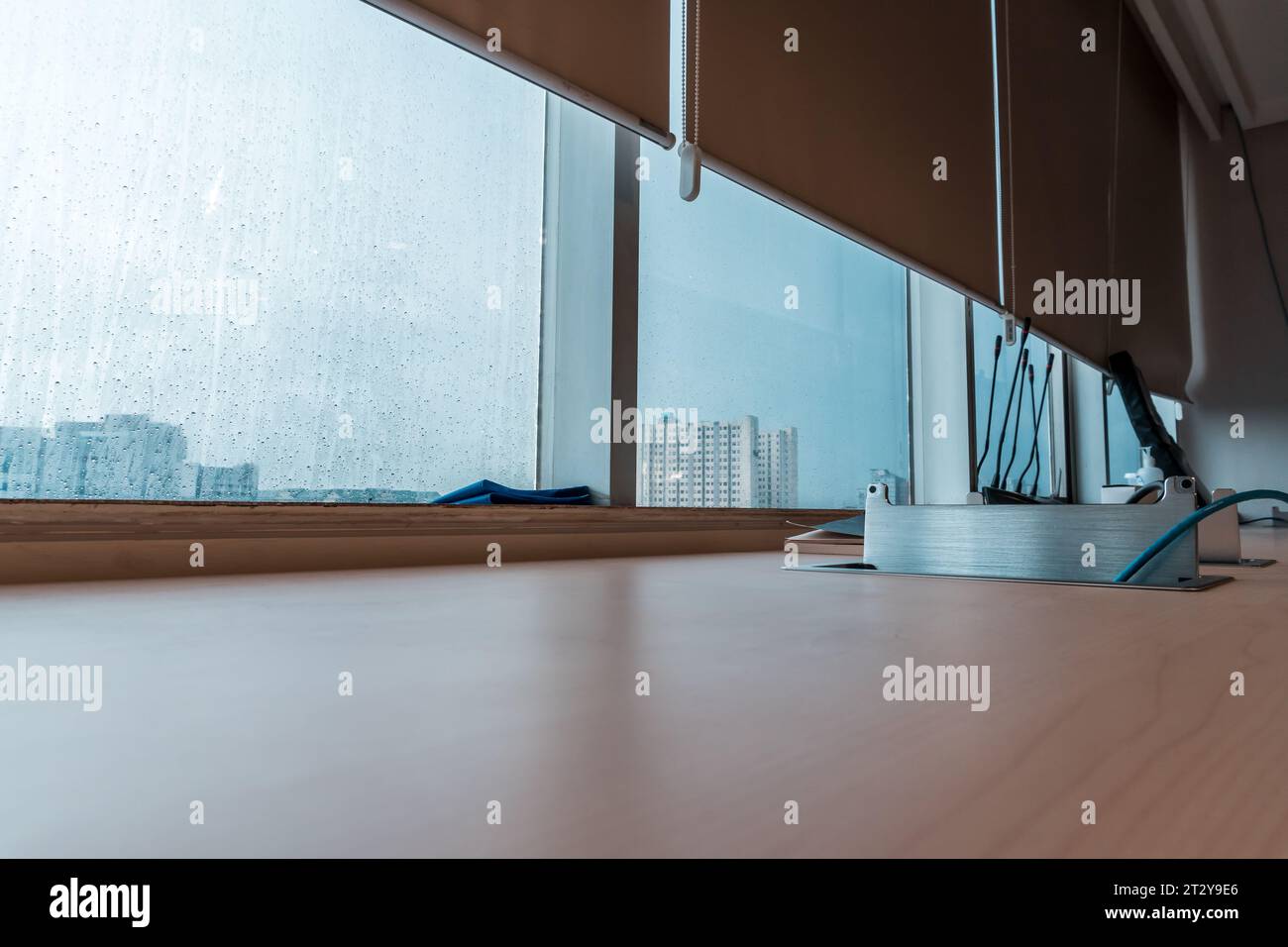 Ruhiges Büroambiente mit regengetränktem Schreibtisch zum Fenster Stockfoto