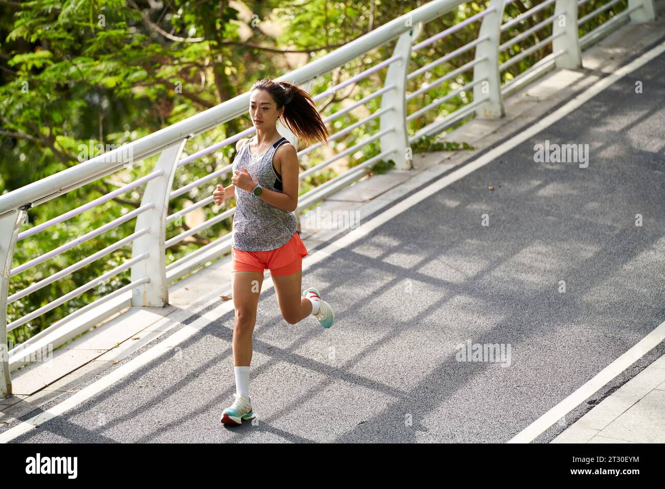 Junge asiatische Frau, die draußen im Park joggt Stockfoto