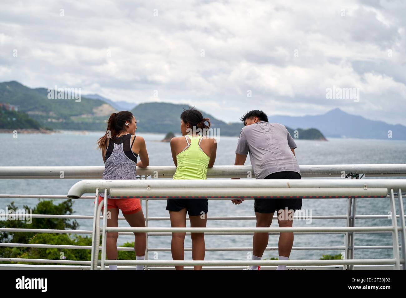 Rückansicht junger asiatischer Leute, die sich entspannt draußen am Meer unterhalten Stockfoto