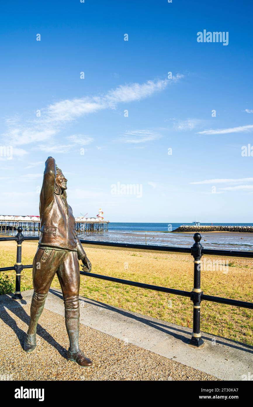 Amy Johnson Statue von Stephen Melton an der Küste von Herne Bay. Ich trage ein Fliegerkostüm aus den 1940er Jahren. Herne Bay Pier im Hintergrund. Blauer Himmel. Stockfoto