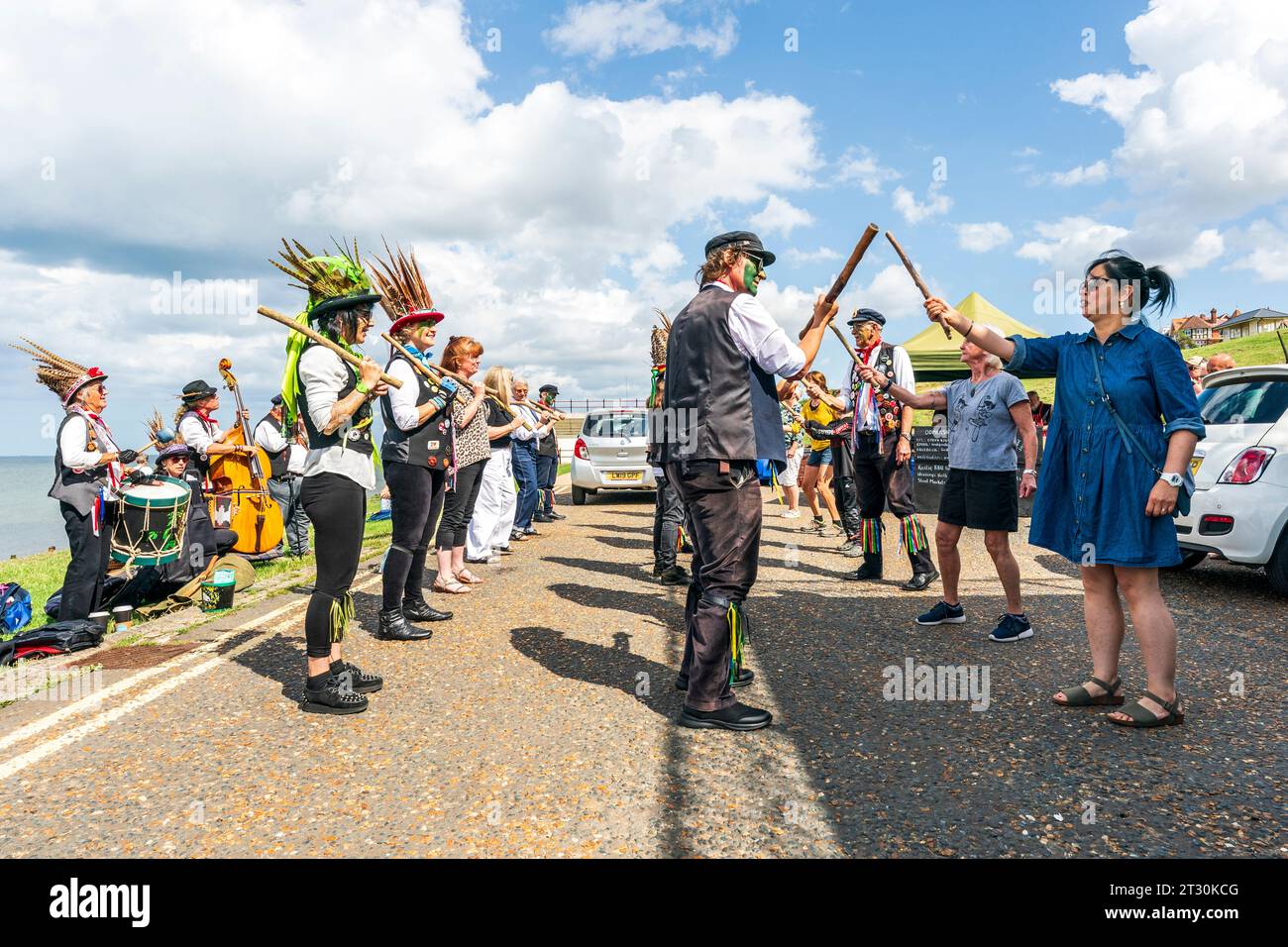 Dead Horse Morrismen halten Stöcke und tanzen mit den Bürgern an der Küste von Herne Bay im Sommer. Heller Sonnenschein und blauer Himmel. Stockfoto