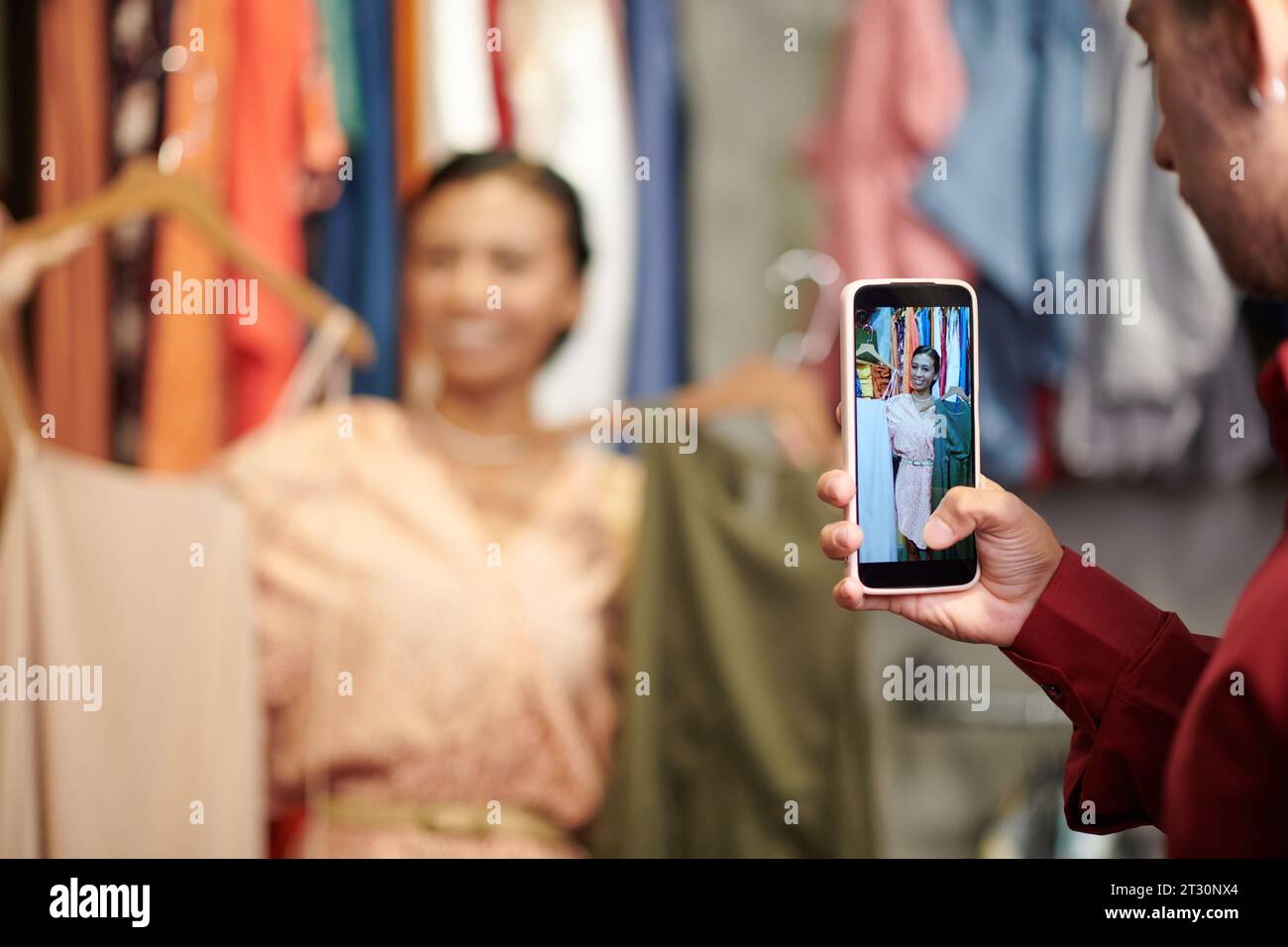 Junger Mann, der ein Foto von einer Freundin mit Kleidern für ihren Fashion-Blog macht Stockfoto