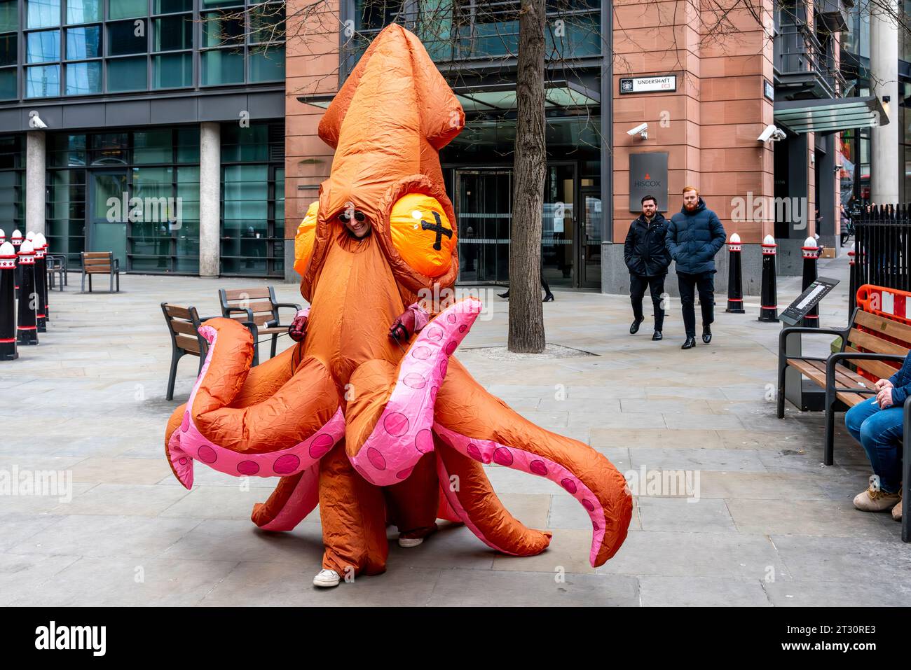 Eine junge Frau in einem Squid-Kostüm, die durch die City of London, London, Großbritannien läuft. Stockfoto