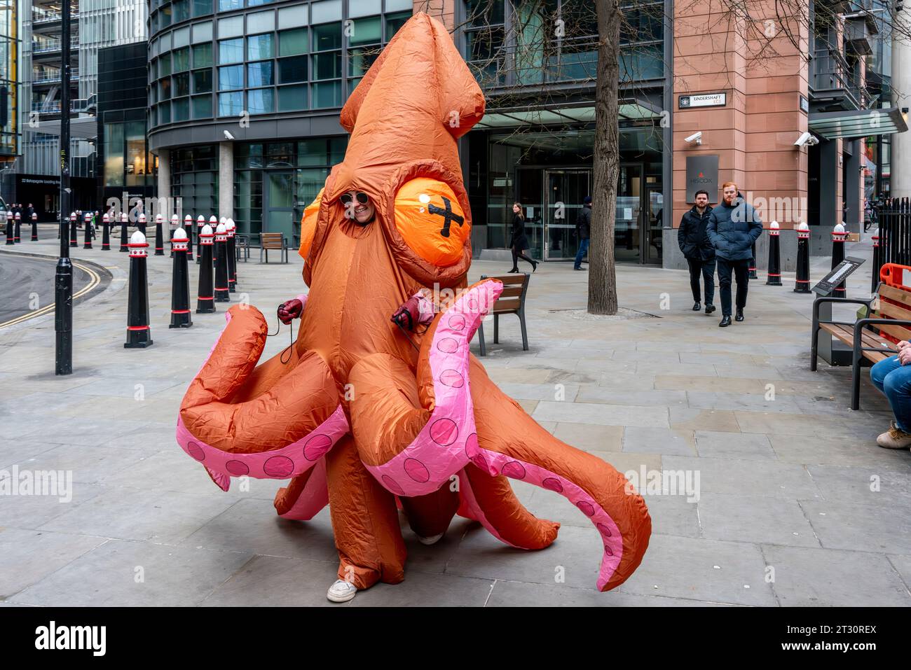 Eine junge Frau in einem Squid-Kostüm, die durch die City of London, London, Großbritannien läuft. Stockfoto