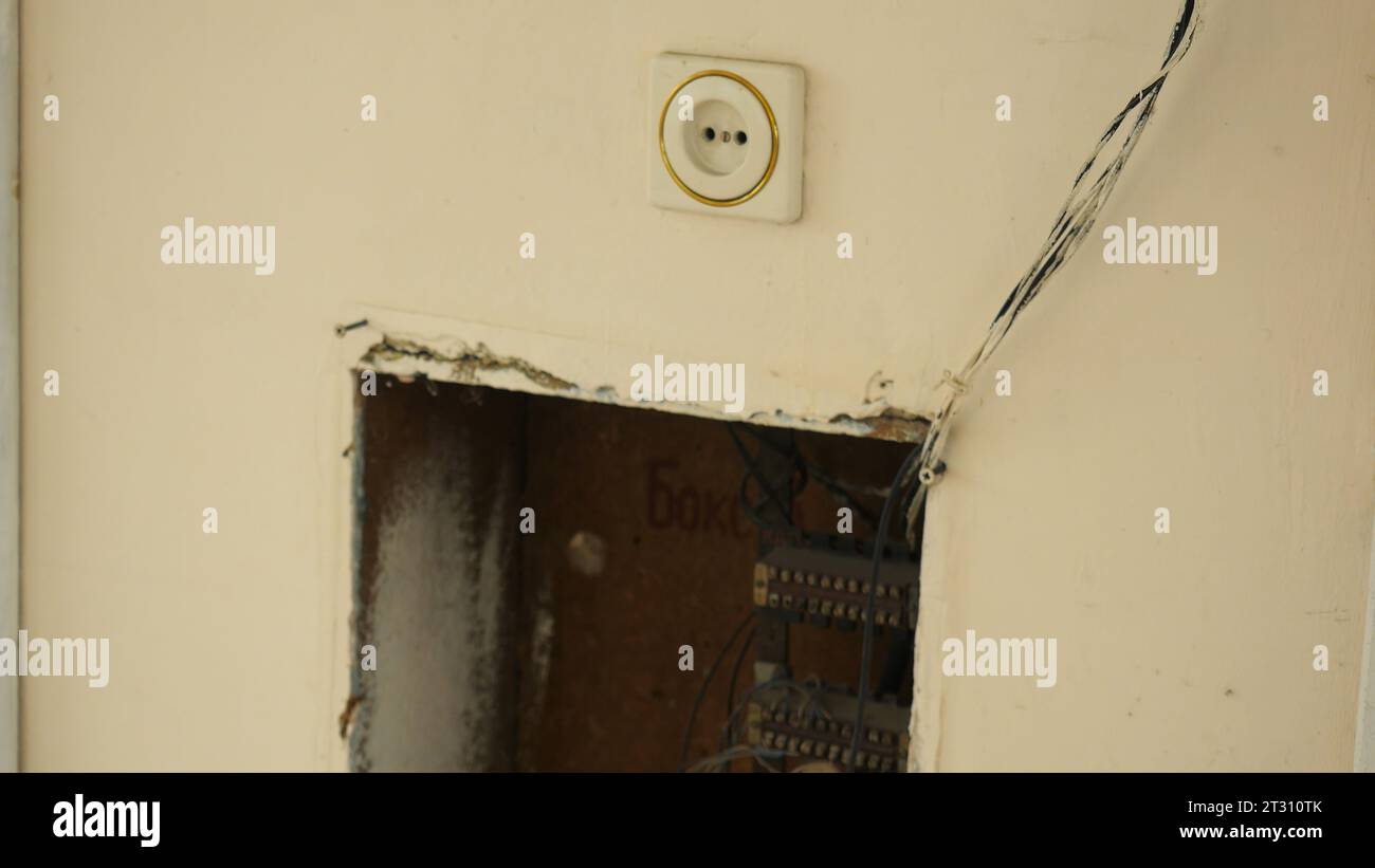 Der alte elektrische Schild in der Wand des alten Hauses. Archivmaterial. Kabel mit Rechnung und Steckdose in der Wand des alten Hauses. Elektrik des alten Dorfhauses Stockfoto