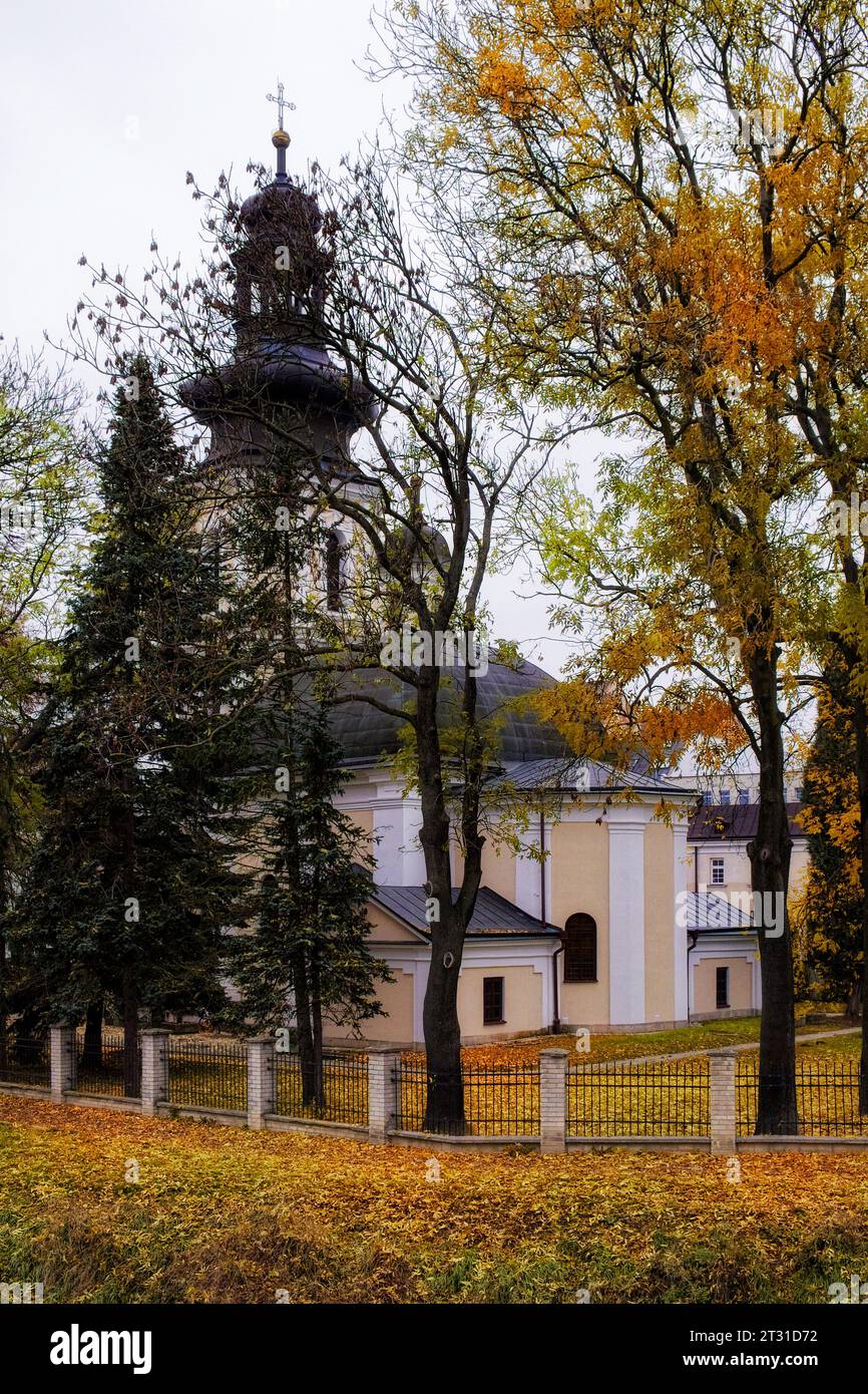 Römisch-katholische Kirche St. Nikolaus, Zamosc. Alte katholische Kirche umgeben von Herbstbäumen, Landschaft. Stockfoto