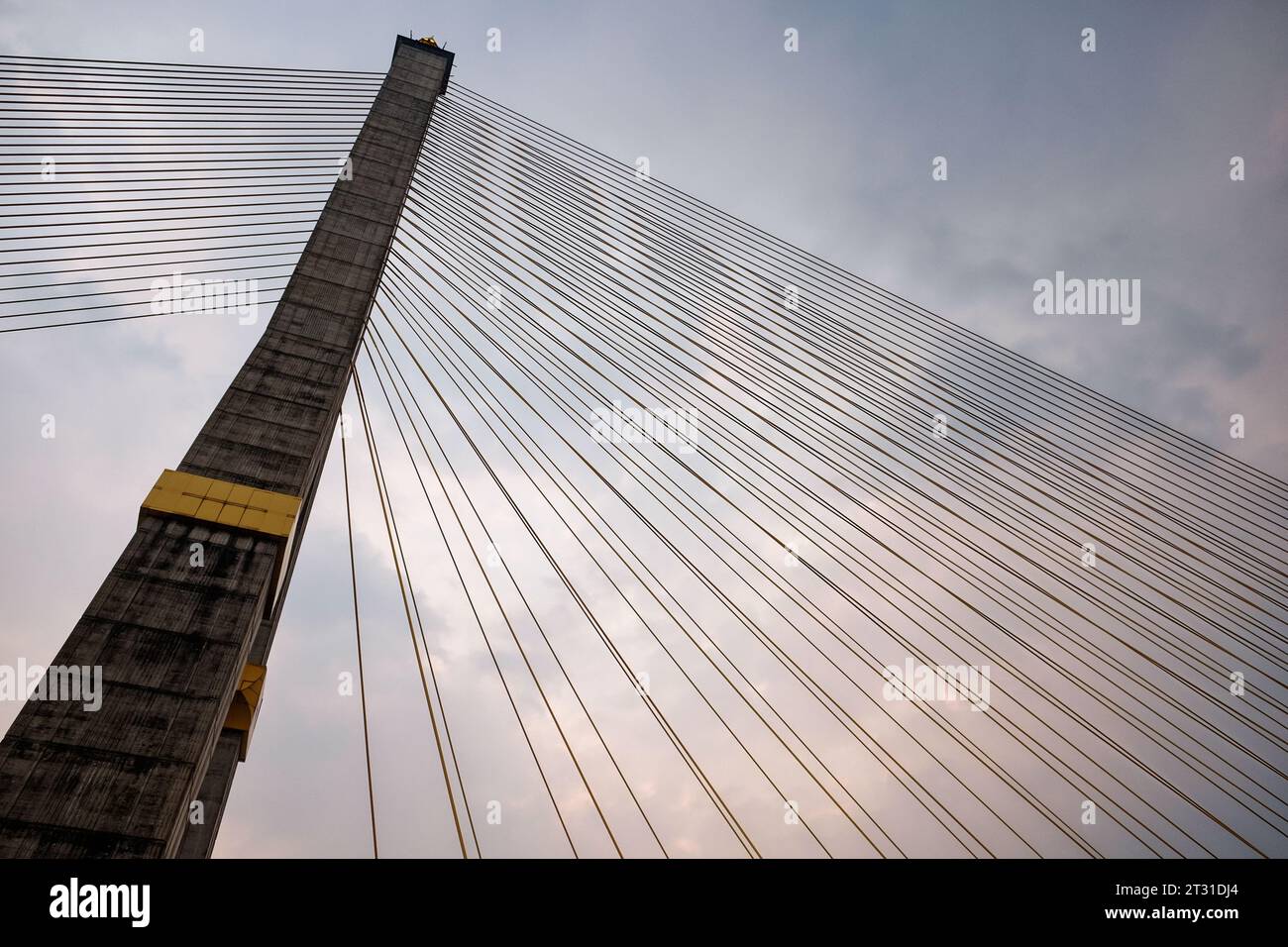 Inmitten eines bewölkten Himmels sorgt ein hoch aufragender Betonpylon einer Kabelbrücke mit harfenartigen Kabeln für Aufmerksamkeit. Stockfoto