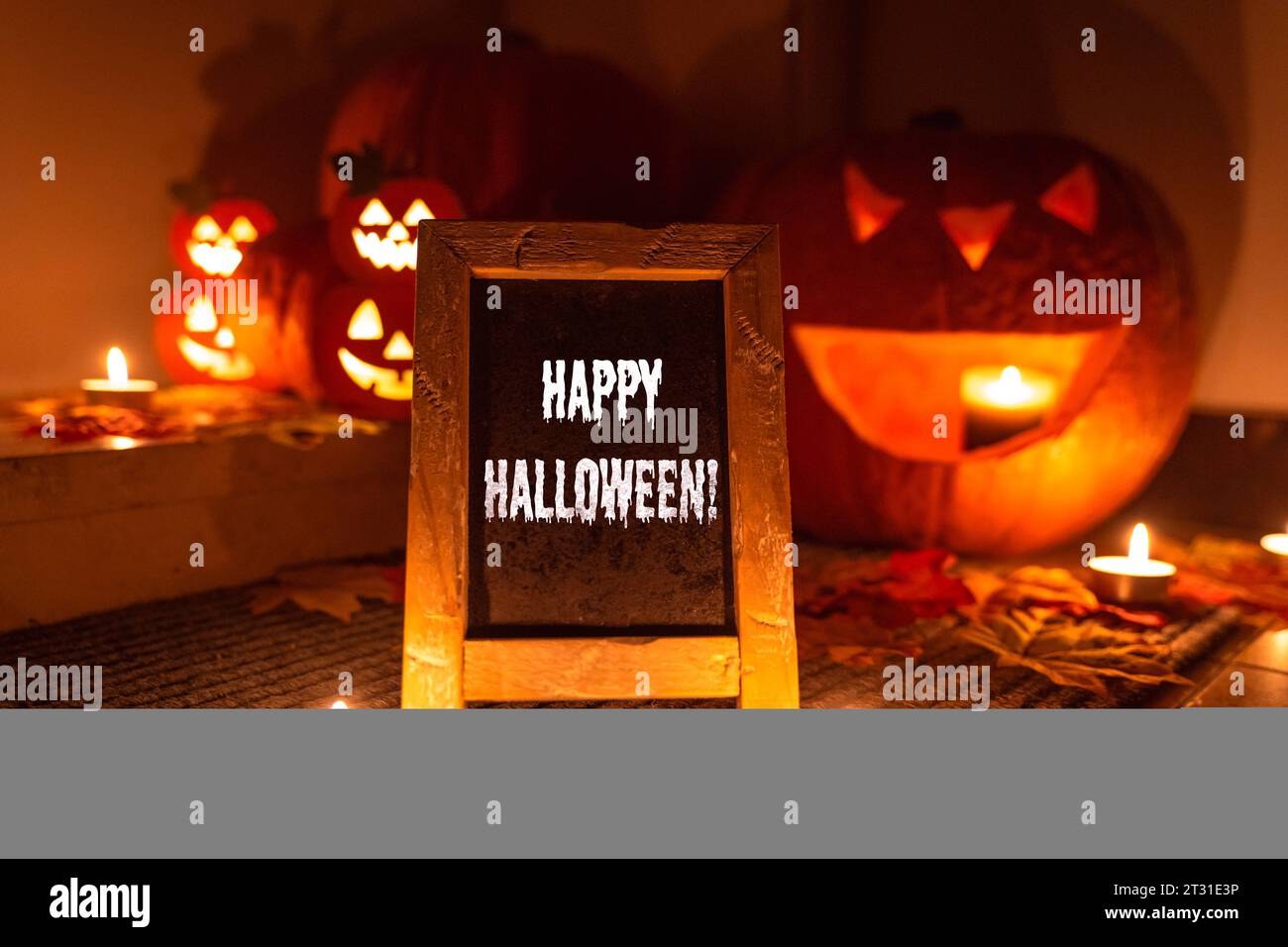 22. Oktober 2023: Kürbis Dekoration bei Nacht vor einer Wohnungstüre mit leuchtenden Kerzen und einer Tafel mit einem Halloween Gruß, Happy Halloween FOTOMONTAGE *** Kürbis Dekoration bei Nacht vor einer Wohnungstüre mit leuchtenden Kerzen und einer Tafel mit einem Halloween Gruß, Happy Halloween FOTOMONTAGE Credit: Imago/Alamy Live News Stockfoto