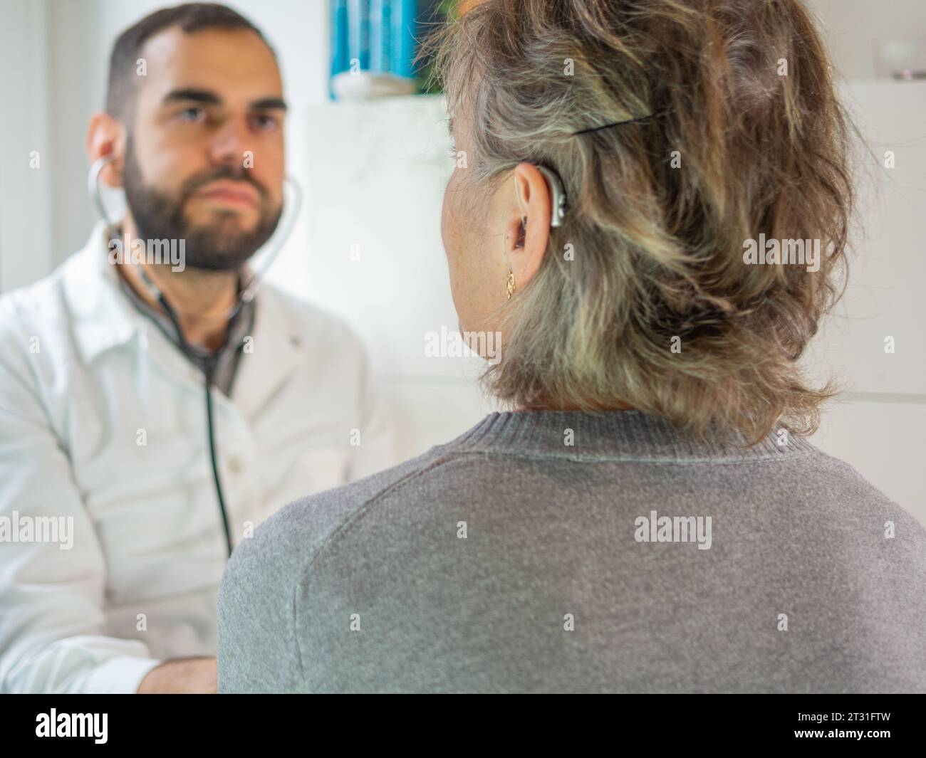 Junger Arzt mit Stethoskop bei seinem Patienten Stockfoto