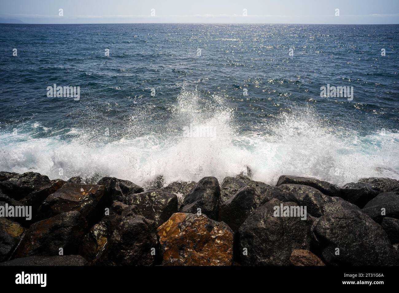 Wasserspritzer auf den Felsen des Ozeans an einem sonnigen Tag. Stockfoto