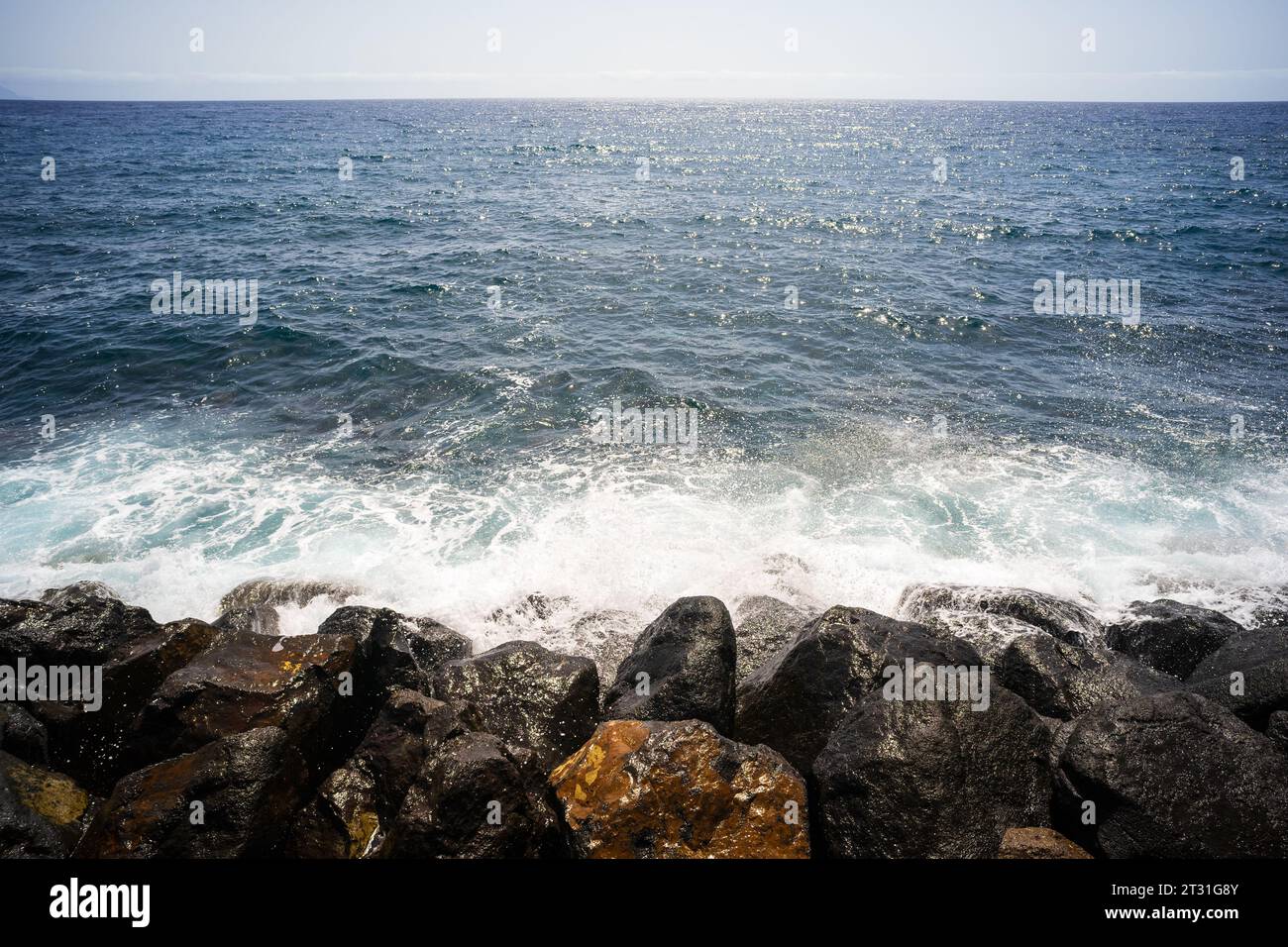 Wasserspritzer auf den Felsen des Ozeans an einem sonnigen Tag. Stockfoto