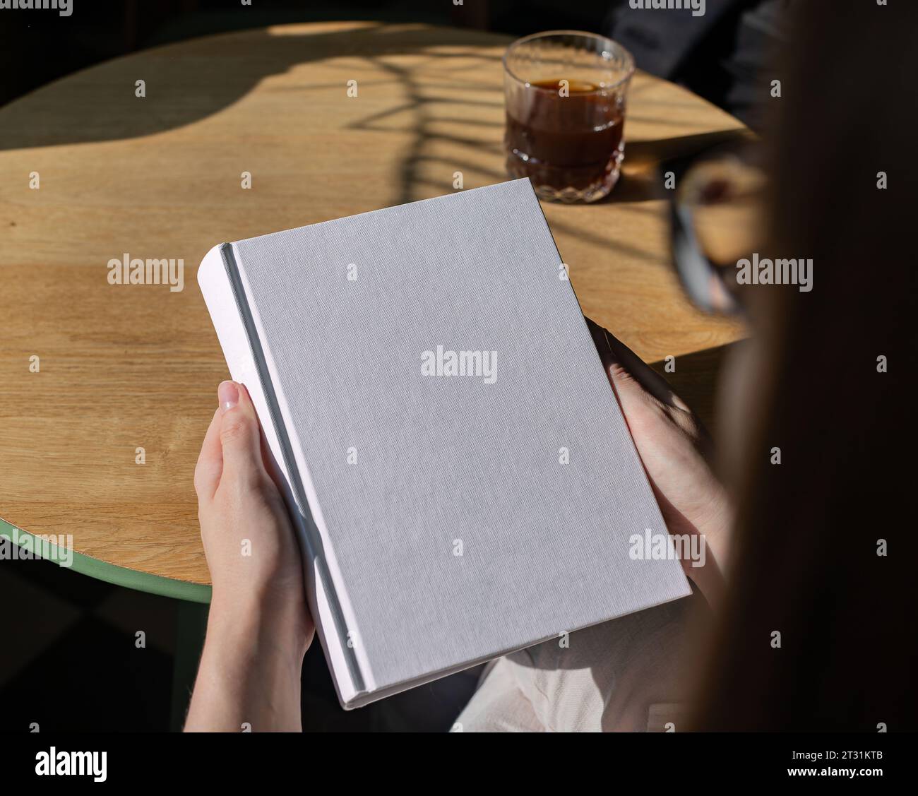 Buchcover-Mock-up, Hand hält leere, saubere Hardcover-Mockup auf Holztisch Stockfoto