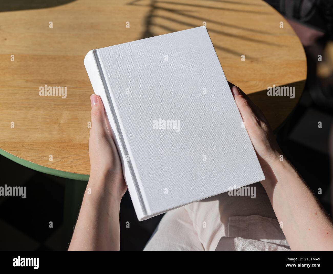 Buchcover-Mockup, Hand hält leere, saubere Hardcover-Mock auf Holztisch Stockfoto
