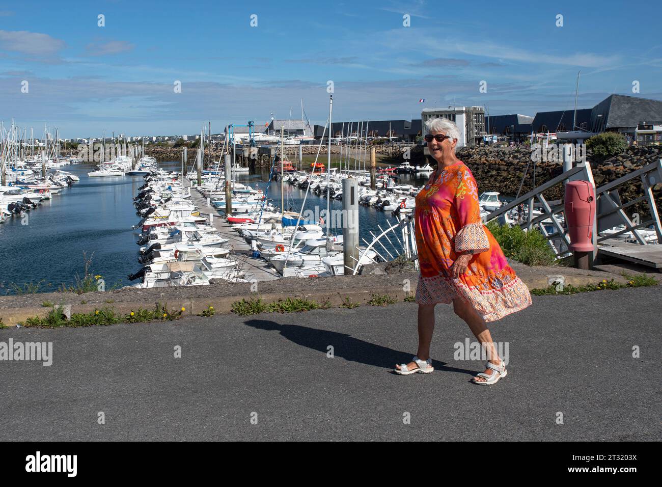 Eine ältere Frau schlendert entlang des Hafens und der Stadt Pornichet in der Bretagne in Frankreich Stockfoto