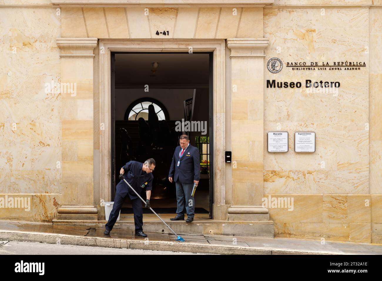 Bogota, Kolumbien - 2. Januar 2023: Mann reinigt den Eingang zum Botero Museum, während ein Sicherheitsbeamter mit ihm spricht Stockfoto