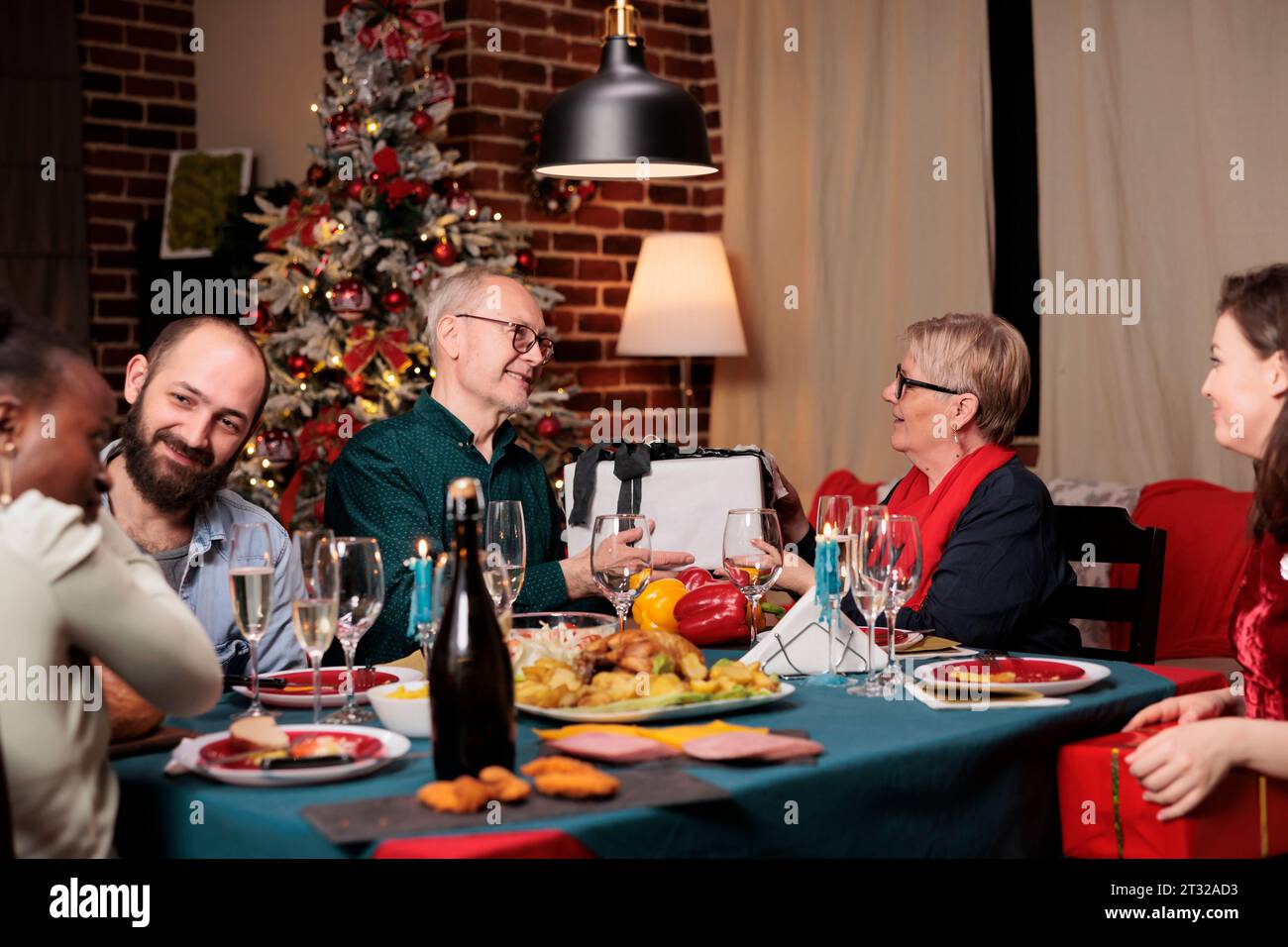 Seniorenpaar tauschen Geschenke an Weihnachten aus, teilen Glück und weihnachtsgeist im dezember zu Hause. Fröhliche Oma und Opa feiern das Winterfest mit festlicher Dekoration. Stockfoto