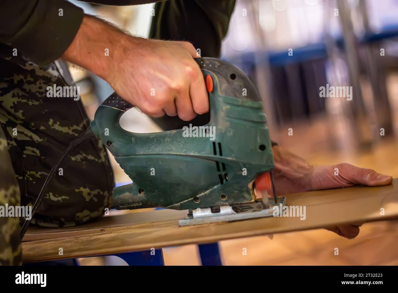 Handwerkskunst der Tischlerei: Ein Handwerker bedient geschickt eine elektrische Stichsäge, um Holzsperrholz für einzigartige Möbelstücke zu schneiden. Stockfoto