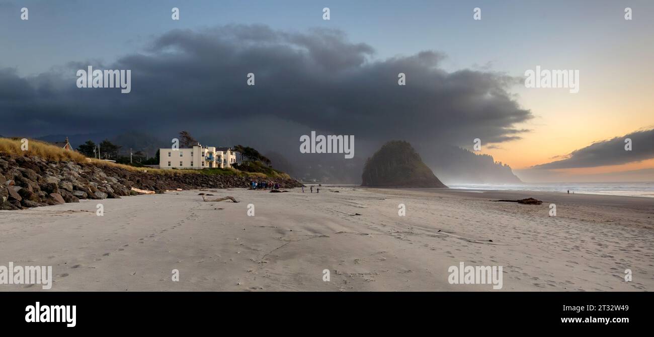 Sandstrand mit Ferienhäusern und dem Meer Stack Proposal Rock bei Sonnenuntergang in Neskowin, Oregon Stockfoto