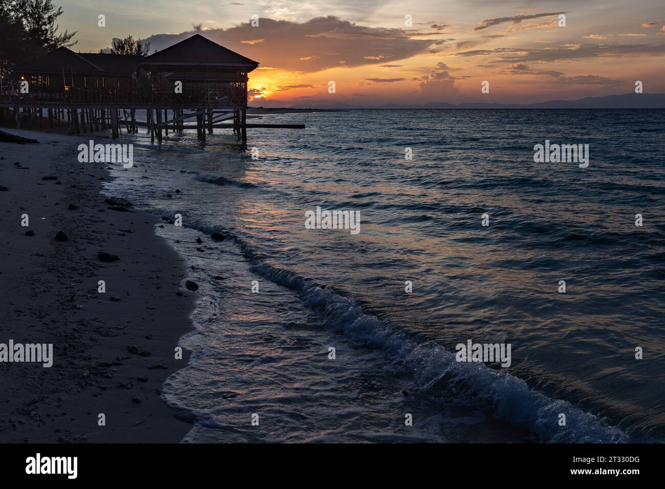 Sonnenaufgang am Dock und Pavillon an einem tropischen Strand und sanfte Wellen Rollen herein Stockfoto