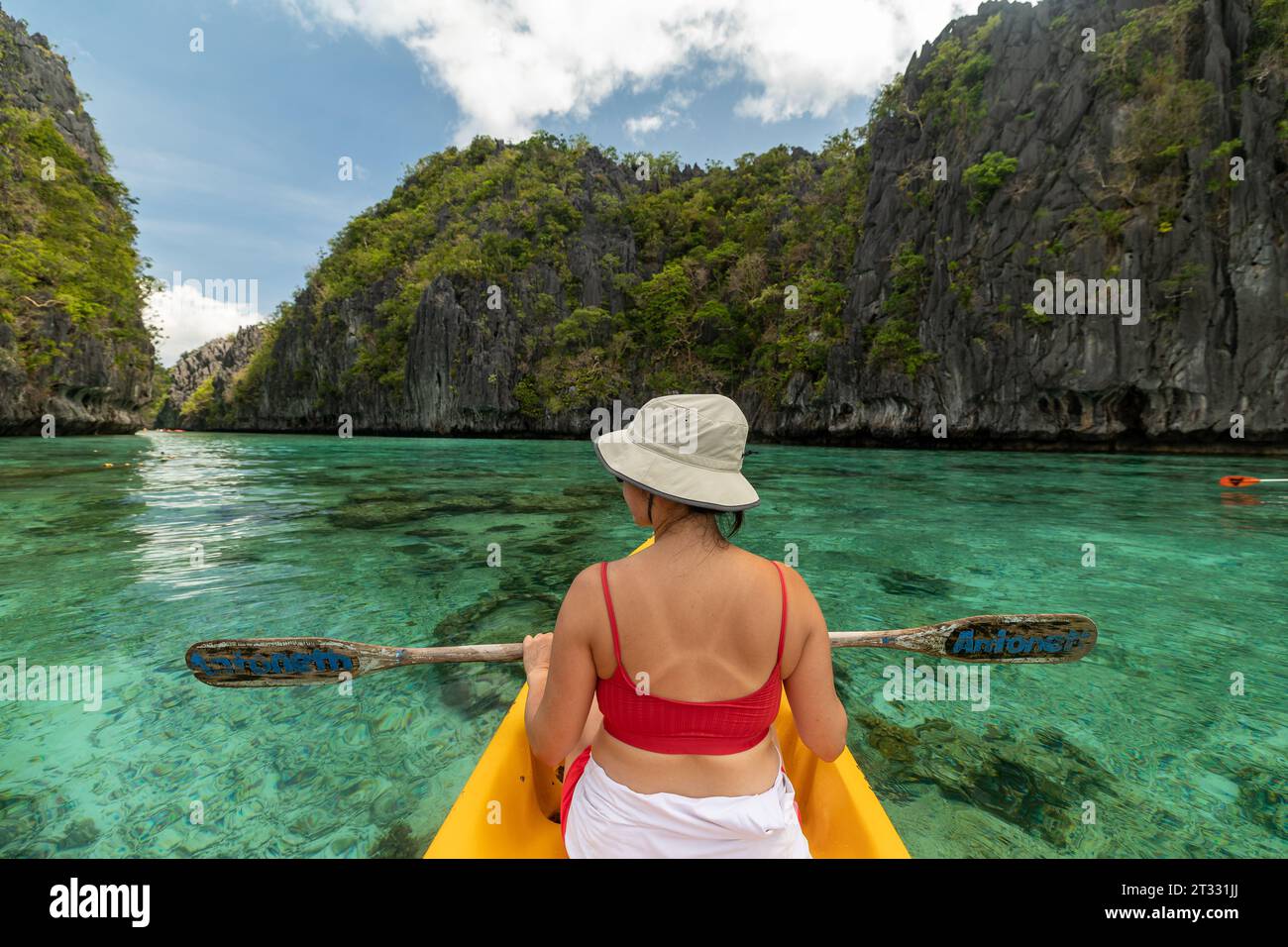 Kajakfahrer genießen das blau-grüne Wasser der wunderschönen versteckten tropischen Bucht inmitten von Karstvorsprüngen Stockfoto