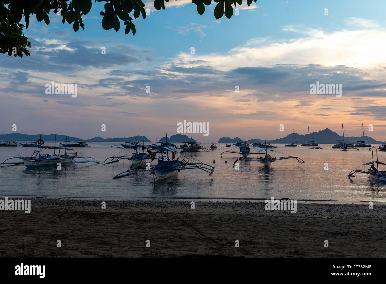 Traditionelle philippinische banca-Boote mit Stützauslegern vor dem Strand bei Sonnenuntergang im tropischen Paradies Stockfoto