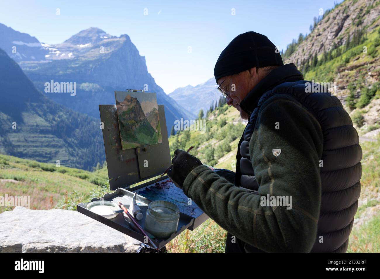 Ein Plein Air-Maler arbeitet an einem Gemälde von Paradise Meadow entlang der Going-to-the-Sun Road im Glacier National Park, Montana. Stockfoto