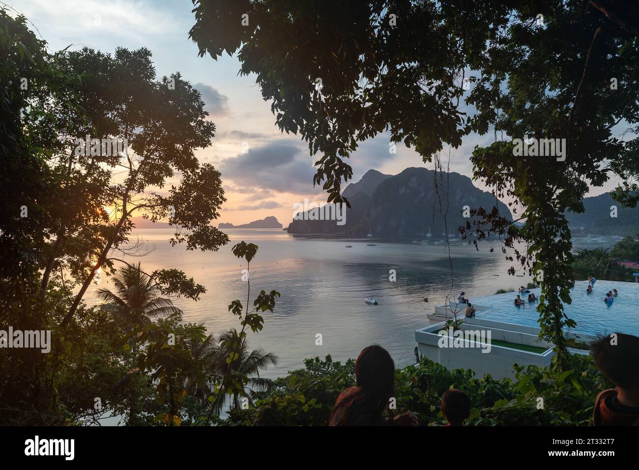 Die Menschen beobachten den wunderschönen Sonnenuntergang in der tropischen Bucht, die mit malerischen Karstkalksteinformationen gefüllt ist Stockfoto