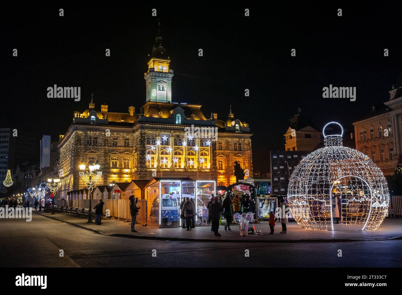 Bild des novi Sad weihnachtsmarkts vor dem trg Slobode Platz mit Menschen bei Nacht. Novi Sad in Serbien wird zu einem weihnachtstourismus Stockfoto