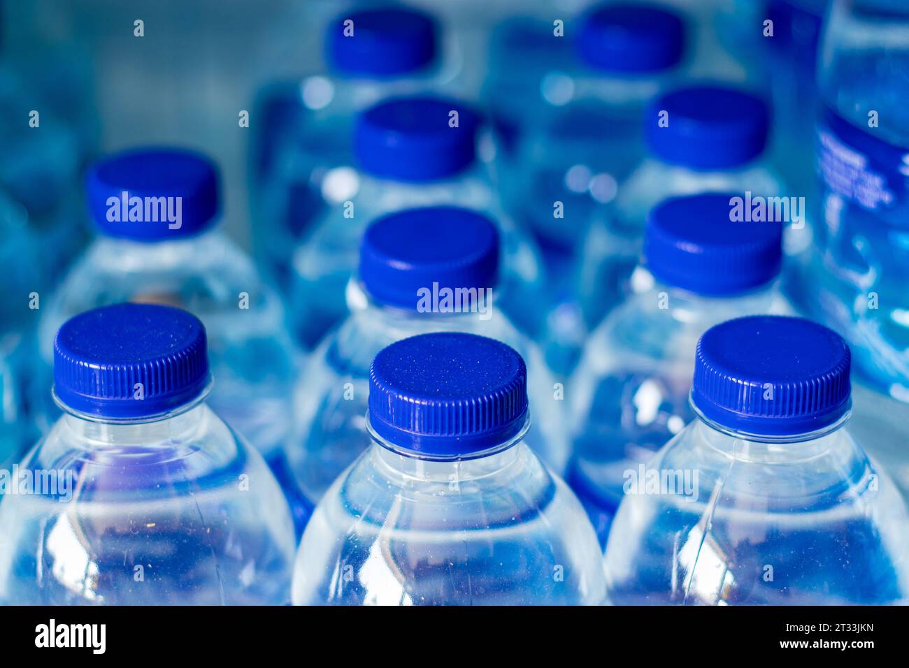 Mineralwasserflaschen in einer Reihe mit blauen Kappen Stockfoto