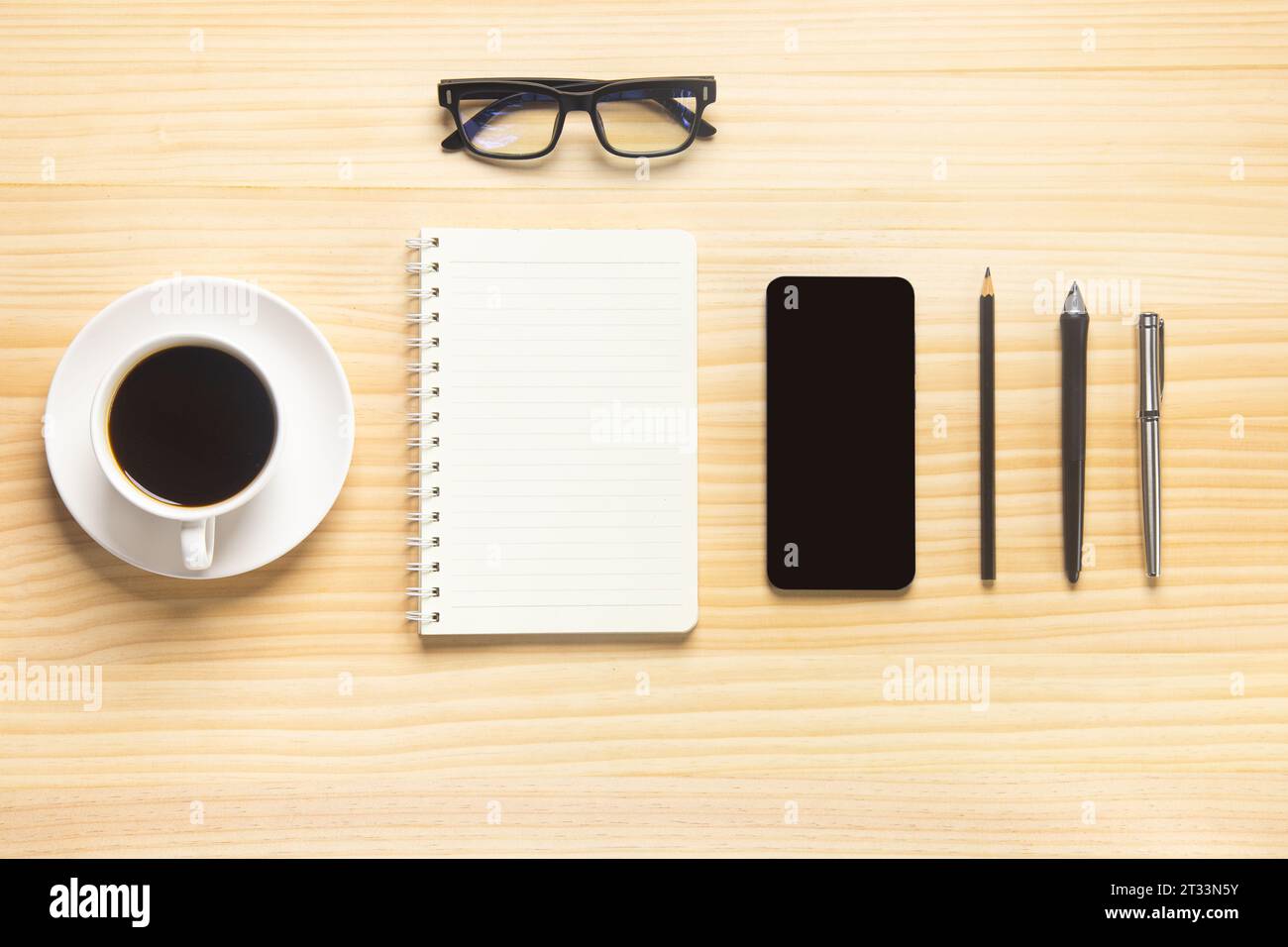 Holzschreibtischbüro mit Laptop, Smartphone und anderen Arbeitsmaterialien mit einer Tasse Kaffee. Draufsicht mit Kopierraum für die Texteingabe. Arbeitsbereich des Konstrukteurs o Stockfoto
