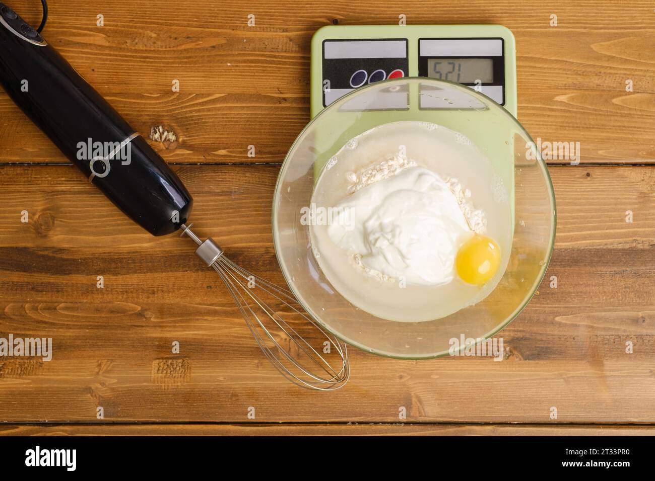 Mehl, Ei, Wasser und Sauerrahm in einer Schüssel auf einer Küchenwaage, Blick von oben Stockfoto