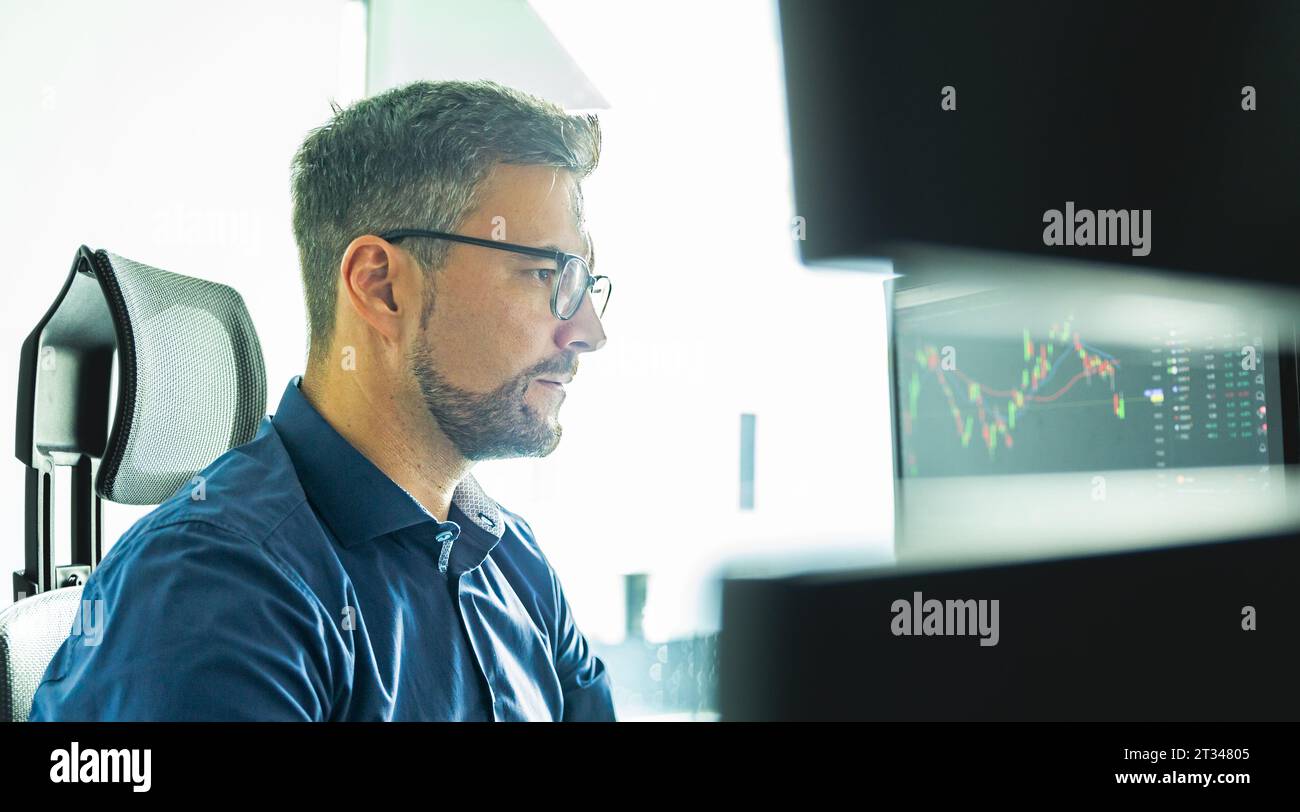 Männliche Börsenmakler Trading online beobachten, Charts und Analysen der Daten auf mehreren Bildschirmen. Stockfoto