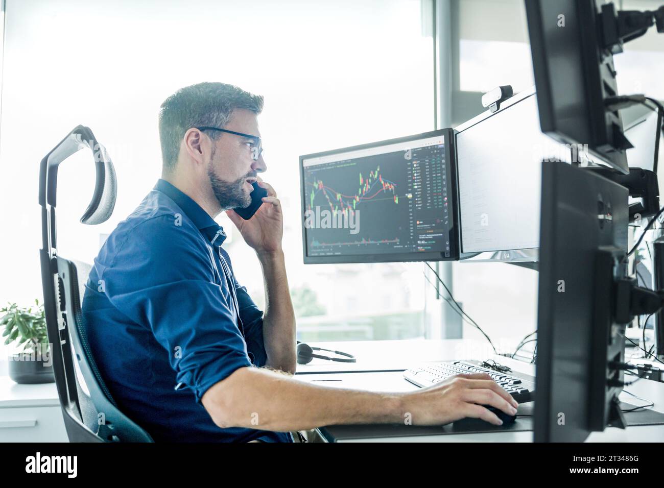Männliche Börsenmakler Trading online beobachten, Charts und Analysen der Daten auf mehreren Bildschirmen. Stockfoto